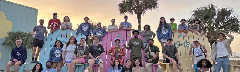 A group of people sat outside together in giant chairs on the beach